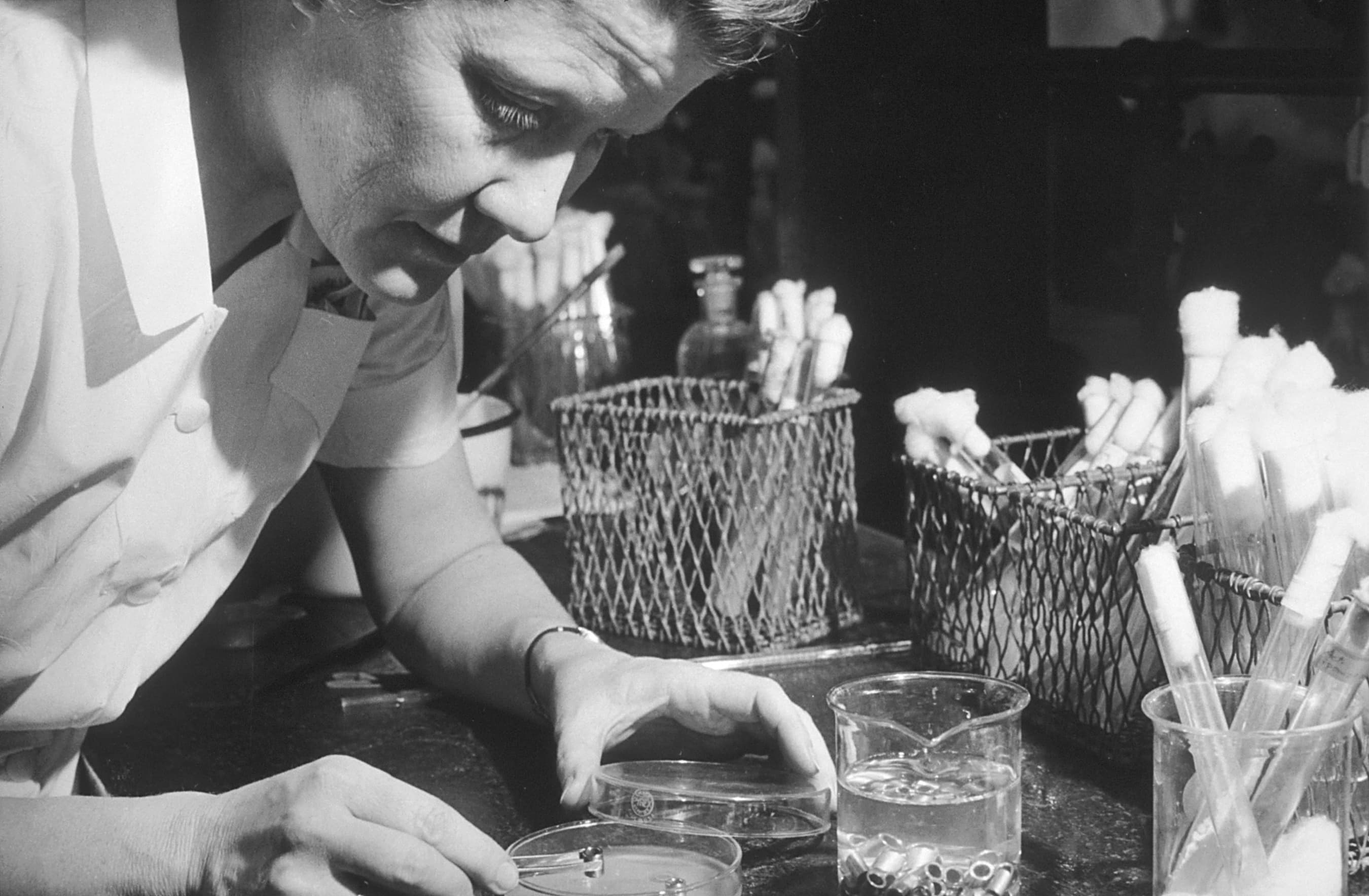 Black-and-white photograph of a scientist performing a streptomycin assay at Rutgers University.